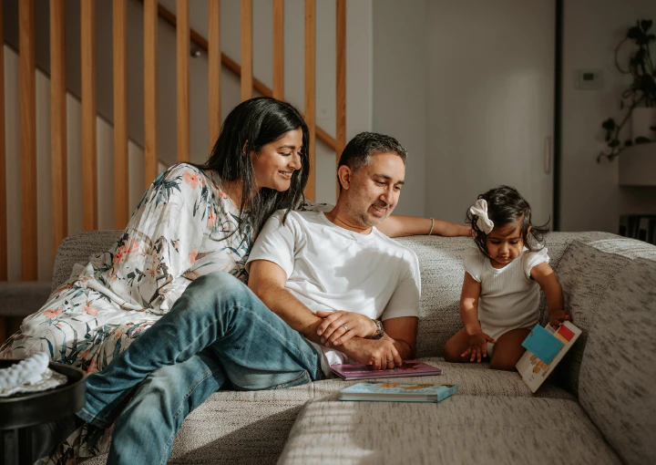 lifestyle-family-photo-at-home lifestyle family photo session in their home. Pictured couple with daughter on their couch
